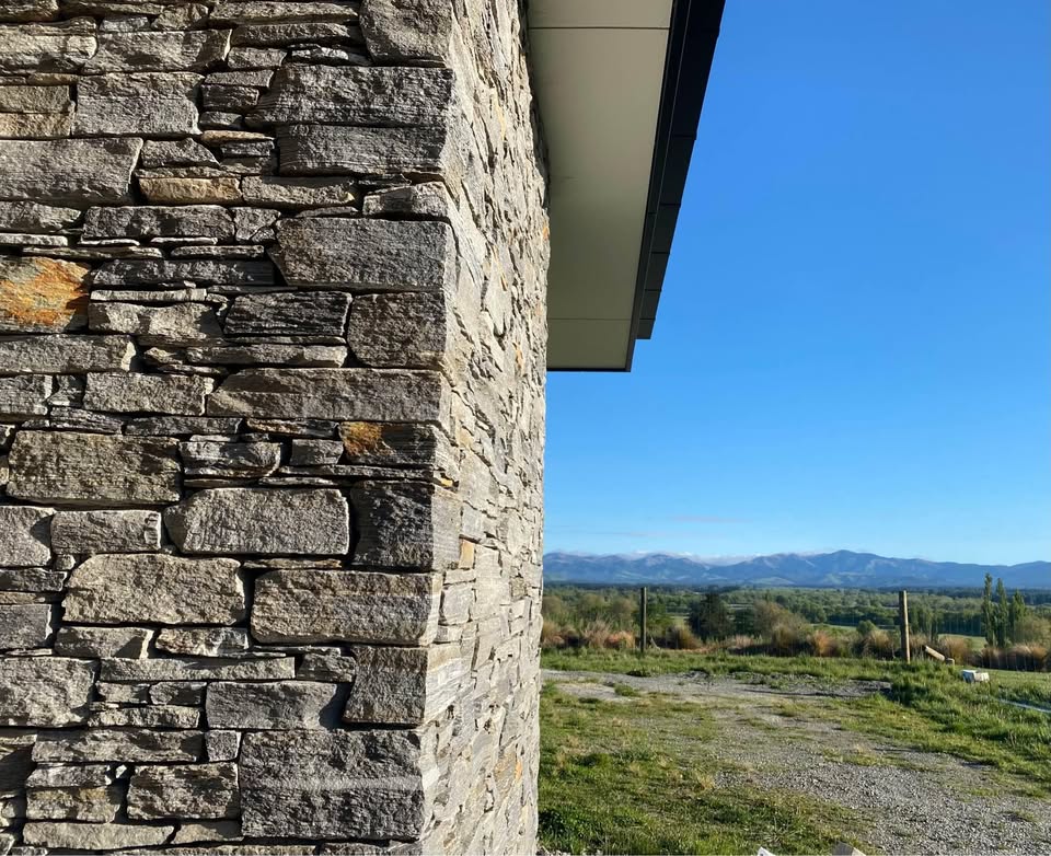 Dry-stacked schist pillar with mountains behind